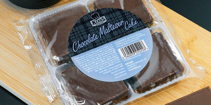 Packaged chocolate malted cake on a wooden board with loose pieces beside it.