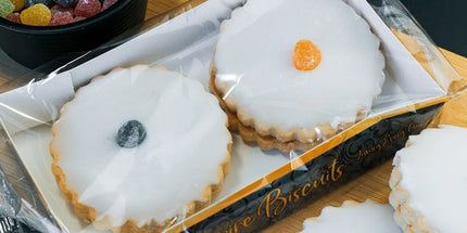 Box of white cookies with colorful centers on a wooden board