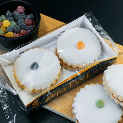 Box of white cookies with colorful centers on a wooden board