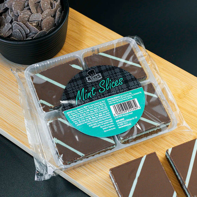 Packaged chocolate mint slices on a wooden board with a black background