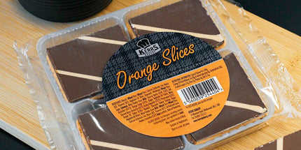 Packaged chocolate orange slices on a wooden board with a black background