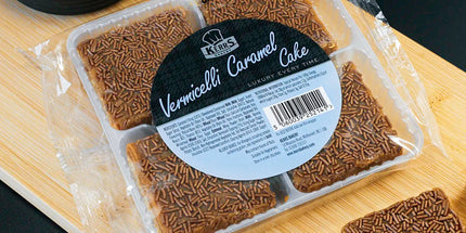 Packaged cake with a label on a wooden board next to slices of cake.